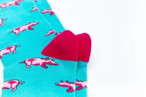 Detailansicht türkisfarbener Baumwollsocken mit rosa Schweinemuster und roten Fersen