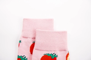 Detail of pink cotton socks featuring ribbed cuffs and red strawberry knit patterns