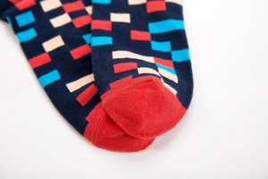 Detailed close-up of navy cotton mid-tube socks with red and blue geometric square patterns
