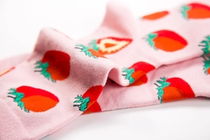 Close-up of pink cotton socks featuring red strawberry patterns and ribbed knit texture
