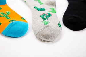 Detail of three mid-calf cotton socks with cactus patterns and colorful knit textures