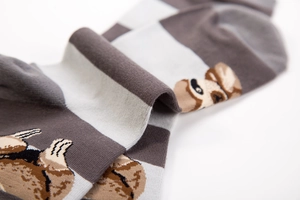 Detail of knitted mid-calf socks featuring a cute cartoon sloth and wide striped pattern