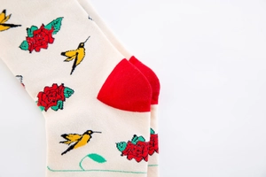 Close-up of floral bird embroidery on cream cotton socks with red heel detail