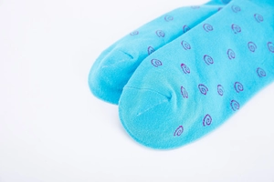 Detail of light blue knitted socks featuring purple spiral patterns and fine toe stitching