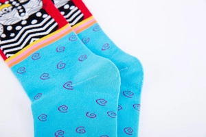 Close-up of crew socks featuring vibrant pop art cat patterns and bold wave textures
