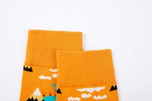 Detail view of ribbed cuffs and vibrant cartoon landscape pattern on orange cotton socks
