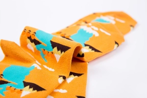 Detailed knit texture of orange crew socks featuring abstract mountain and cloud patterns