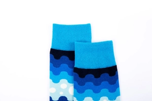Detail of blue gradient knit socks featuring polka dots and wave patterns
