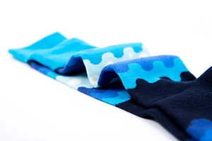 Macro view of cotton crew socks featuring blue wavy patterns and polka dots on white base