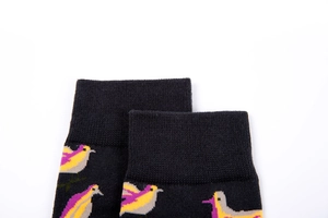 Close-up of ribbed cuffs on black cotton socks featuring vibrant yellow and purple bird patterns