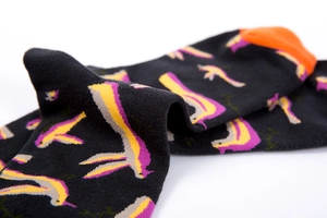 Detail of dark cotton mid-calf socks with orange heels and colorful bird patterns