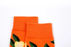 Detail of bright orange cotton socks featuring knitted yellow flowers and ribbed cuff texture
