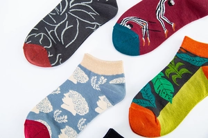 Detail of four artistic cotton low-cut socks featuring creative patterns and ribbed cuffs
