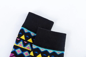 Close-up of ribbed cuffs on colorful geometric knit socks with vibrant triangle patterns