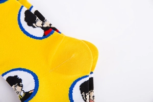 Detail of reinforced heel on yellow knitted sock with pixel art cartoon portrait