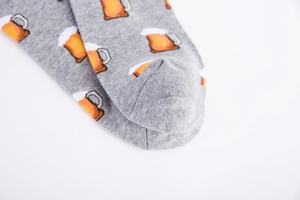 Close-up of gray cotton socks featuring yellow beer mug patterns with knit stitch details