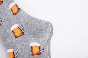 Close-up of grey knit cotton socks featuring orange beer mug patterns and heel detail