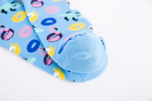 Close-up of light blue cotton socks featuring colorful flamingo and alligator patterns