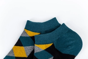 Close-up of argyle pattern low-cut socks featuring teal, yellow, and grey knit textures