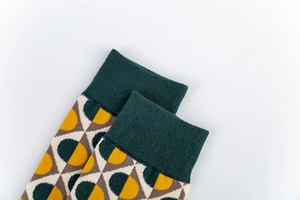 Gros plan des poignets côtelés vert foncé et des motifs géométriques sur les chaussettes