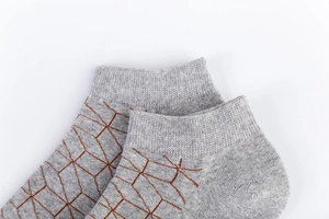 Detailed close-up of light grey cotton socks with brown 3D geometric linear patterns