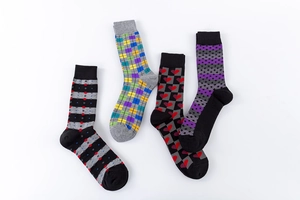 Detail of four men's crew socks featuring assorted geometric and argyle patterns on white background