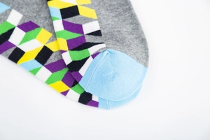 Close-up of grey cotton socks featuring colorful geometric patterns and light blue toe detail