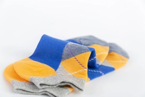 Detail view of blue and yellow diamond pattern knit ankle socks with reinforced gray heels
