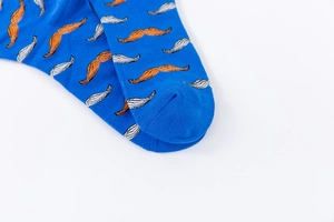 Detail view of cotton crew socks featuring orange mustache patterns on navy blue fabric