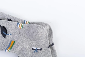 Detail of light gray cotton socks featuring knitted graduation cap and colorful books