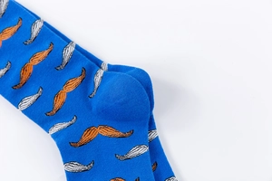 Detailed close-up of blue cotton mid-calf socks featuring orange mustache knit patterns