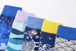Detail of five blue mid-calf socks with ocean wave and whale knitting patterns