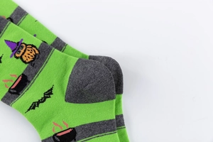 Detail of Halloween socks with green stripes, owl in wizard hat, and bat patterns