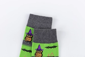 Detail of Halloween crew socks featuring owl in wizard hat and bat patterns on green knit
