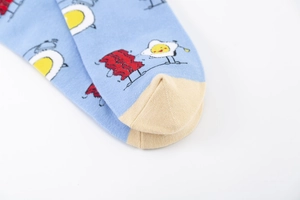 Détail de chaussettes en coton bleu avec motif œuf au plat, bacon et pointe jaune