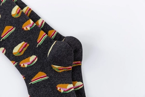 Detail view of dark grey crew socks featuring a colorful sandwich pattern in cotton blend