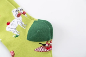 Detail of green cotton crew socks featuring knit alpaca, apple, and picnic basket patterns