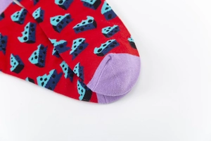 Detail view of colorful red crew socks with blue geometric pattern and purple toe finish
