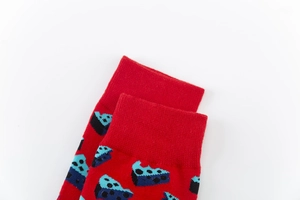 Detail of red cotton socks featuring blue geometric jacquard patterns and ribbed cuffs