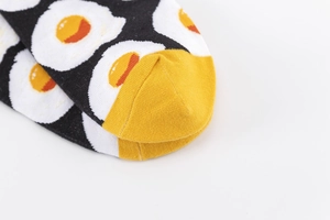 Detailed close-up of cotton knit socks featuring fried egg prints and yellow toe stitching