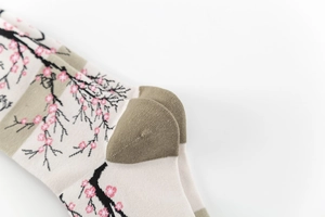 Detail view of cotton socks with pink cherry blossom jacquard and green heel stitching