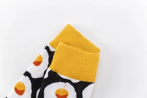Close-up of fried egg pattern and yellow ribbed cuff on these casual crew socks