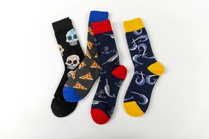 Detail view of colorful mid-calf cotton socks featuring skull, pizza, and narwhal patterns