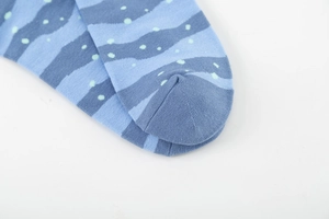 Close-up of cotton crew socks featuring blue waves and mint green pixelated dots texture