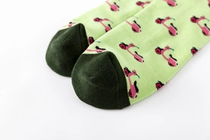 Close-up of green cotton socks featuring pink scooter patterns and reinforced dark toes