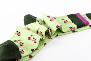 Detail of light green cotton socks with pink scooter prints and purple stripe at the cuff