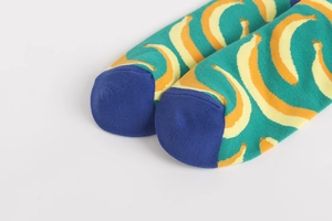 Detail of colorful cotton crew socks featuring vibrant yellow banana print and blue toe