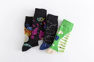 Flat lay of four colorful mid-calf cotton socks with galaxy, star, and golf patterns