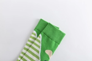 Macro shot of green crew sock with geometric patterns and ribbed elastic cuff detail