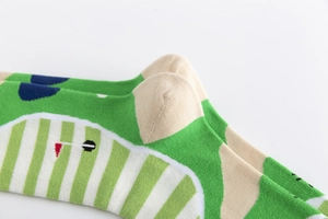 Close-up of green and beige golf theme cotton socks with stripes and flag patterns